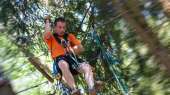 A young man having fun in the acrobatic park in forest